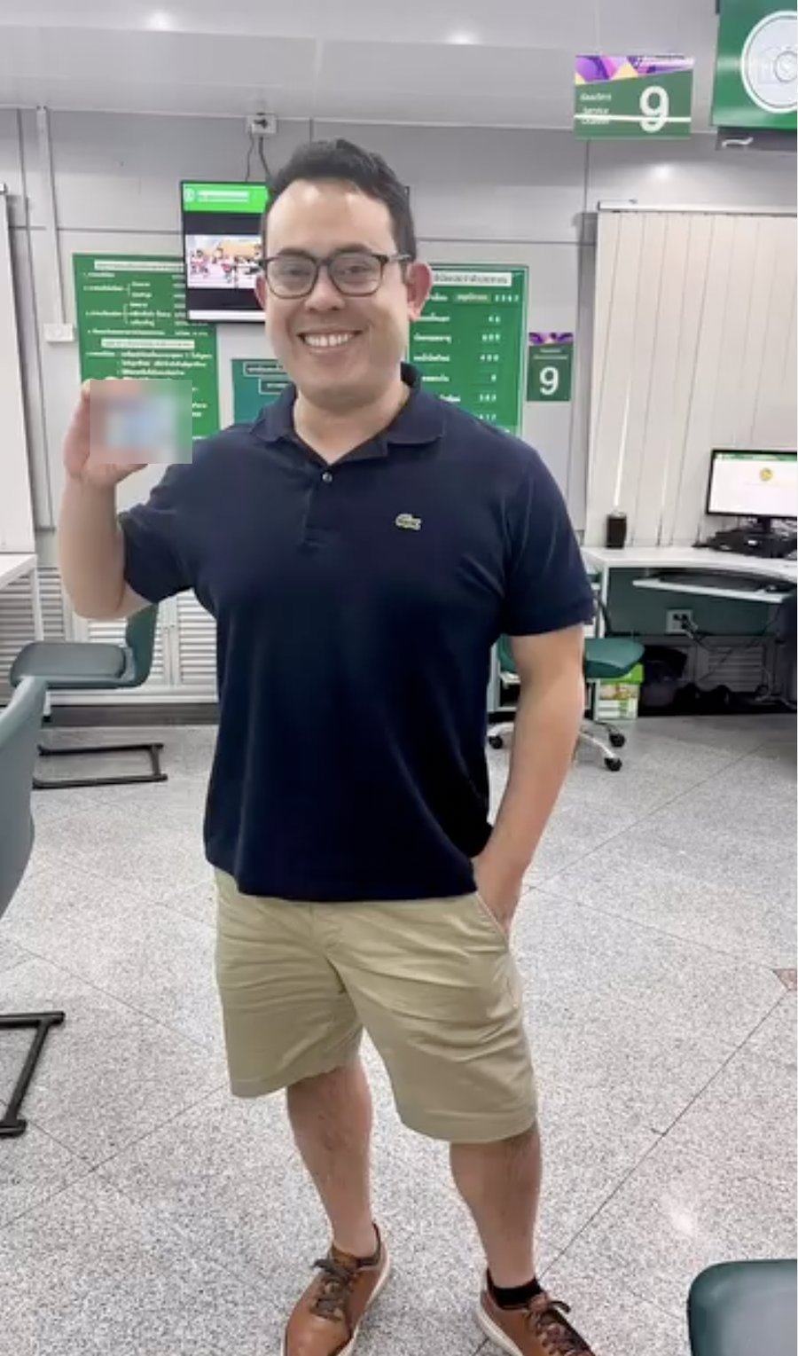 Tony smiling in Thailand while holding a blurred card