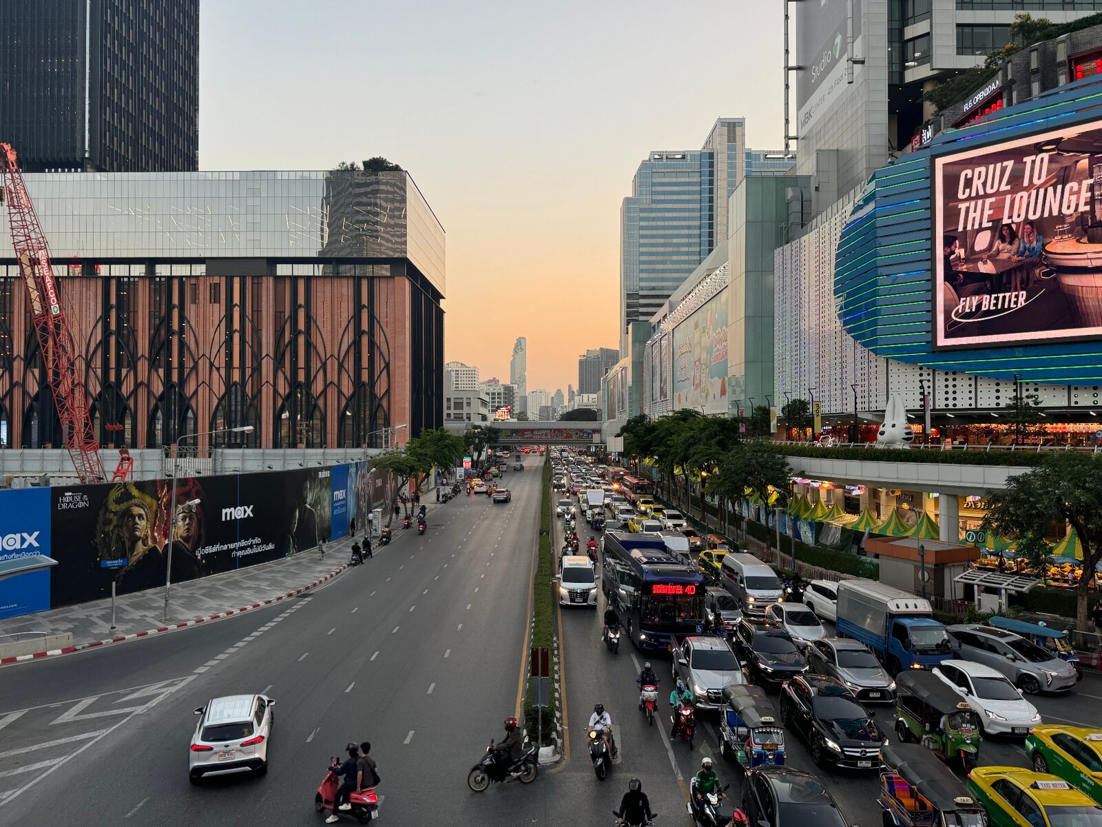 Bangkok city street at sunset with traffic and neon billboards